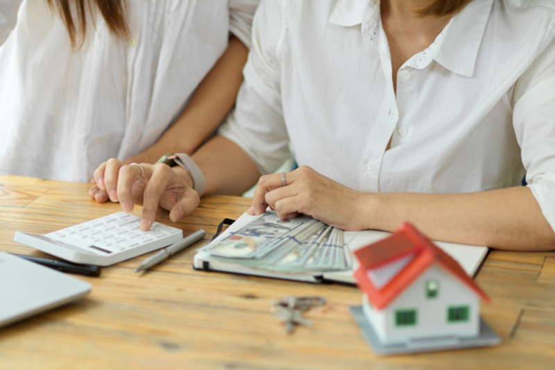 Immobilienmakler Bockenheim tippt auf einem Taschenrechner mit Geld um Immobilie zu bewerten
